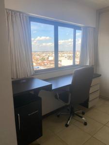 an office with a desk and a large window at Loft no Condomínio Celita Franca Executive ApartHotel in Feira de Santana