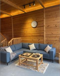 a living room with a blue couch and a clock on a wall at أكواخ البحيرات in Khalij Salman