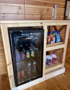 a small refrigerator in a wooden cabinet with drinks at أكواخ البحيرات in Khalij Salman