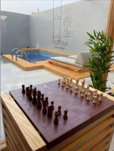 ein Schachbrett auf einem Tisch neben einem Pool in der Unterkunft أكواخ البحيرات in Khalij Salman