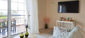 a living room with a couch and a television on a wall at Nama Beach House in rkadiko Chorio