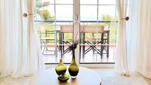 two green vases sitting on a table in front of a window at Nama Beach House in rkadiko Chorio