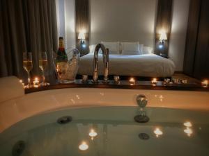 a bathroom with a bath tub with wine glasses and a bed at MB Boutique Hotel - Adults Recommended in Nerja
