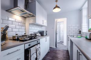 cocina con armarios blancos y fogones en Luxurious Living 2 BR Home MCR, en Mánchester