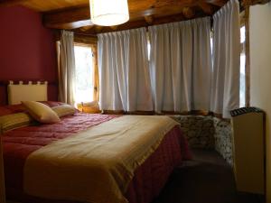 a bedroom with a bed and a window with white curtains at El Rincon de Pehuenia in Villa Pehuenia