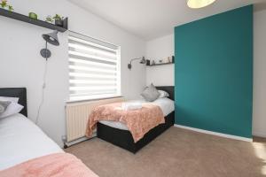 a bedroom with two beds and a blue door at SPECIAL PROMO! Perfect Group Accommodation, 3 Bathrooms Perfect for Contractors and Businesses with relocation Requirement near Harwich Sea Port in Harwich