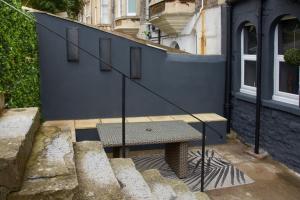 un banc assis à côté d'un mur bleu avec des escaliers dans l'établissement Knightstone Apartment, à Weston-super-Mare