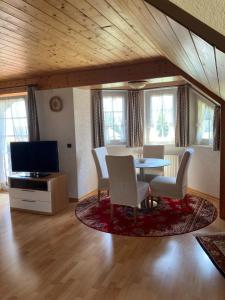 un soggiorno con tavolo, sedie e TV di Wunderschöne Ferienwohnung im Haus Schupp mit bester Aussicht a Wittenschwand