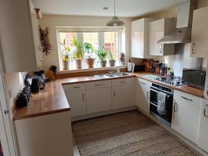 a kitchen with white cabinets and a window with potted plants at 3 bedroom townhouse near Bicester Village in Bicester