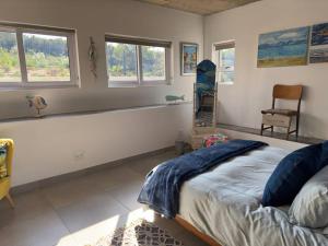 um quarto com uma cama, uma cadeira e janelas em Vincent - Artistic Luxury Suite em Mossel Bay