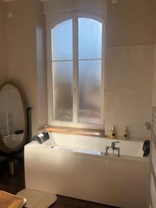 a white bath tub in a bathroom with a window at Appartement de caractère in Mirecourt