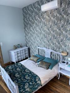 a bedroom with a white bed and a wall at Appartement de caractère in Mirecourt