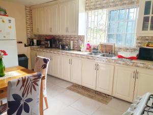 a kitchen with white cabinets and a sink and a window at NaturalB's Cozy Getaway in Montego Bay