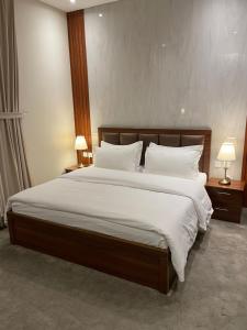 um quarto com uma cama grande com lençóis brancos e almofadas em بريفير للأجنحة الفندقية Privere Hotel Suites em Riyadh