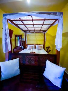 ein Schlafzimmer mit einem Himmelbett und weißen Kissen in der Unterkunft Ananda Homestay Lemukih in Singaraja