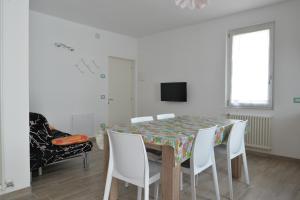 a dining room with a table and white chairs at Appartamenti Nadalini in Levico Terme