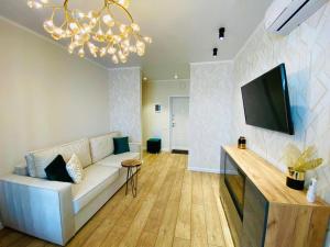 Il comprend un salon doté d'un canapé blanc et d'une télévision à écran plat. dans l'établissement Apartament LETO, à Astana