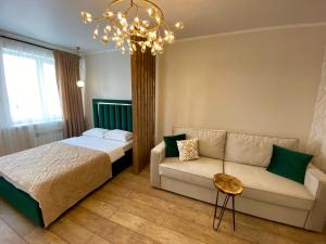 - une chambre avec un lit, un canapé et un lustre dans l'établissement Apartament LETO, à Astana