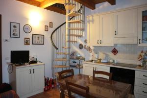 a kitchen with a table and a spiral staircase at La dimora delle corti in Vanzone