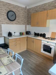 una cocina con armarios de madera y un reloj en la pared en hewitt place en Crewe
