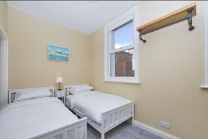 two beds in a room with a window at Stylish beachfront apartment in historic Deal in Kent