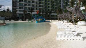 een strand met stoelen en een speeltuin voor een gebouw bij Azure Urban Resort Residences Staycation in Manilla