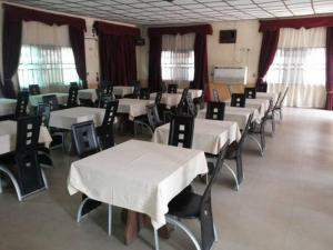 una habitación con mesas y sillas con manteles blancos en Room in Lodge - Garentiti Apartment - Silver Room, en Iyiba