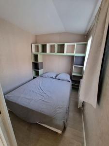 a small bedroom with a bed and shelves at Chalet 6 pers à 10km de Cabourg in Dozulé
