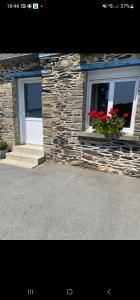 a stone building with two windows with red flowers at Studio du Quintinet in Le Quillio