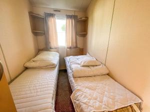 Duas camas num pequeno quarto com uma janela em Lovely 6 Berth Caravan At Skipsea Sands Park In Yorkshire Ref 41053sf em Barmston