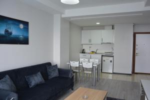 a living room with a black couch and a kitchen at Hera Emlak in Kırac