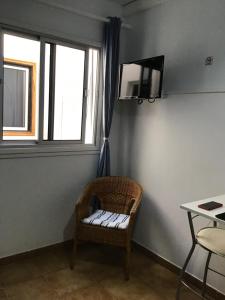Cette chambre dispose d'une chaise, d'une télévision et d'une fenêtre. dans l'établissement Apartamentos Playamar II, à Valle Gran Rey
