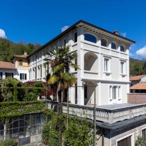 un bâtiment blanc avec un palmier en face dans l'établissement Villa Agnona Appartamento in Villa, à Borgosesia
