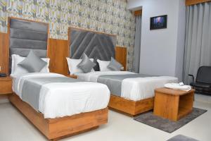 a hotel room with two beds and a chair at Hotel Green Park in Gandhinagar