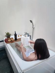 a woman laying in a bath tub reading a book at MIHA Villa in Cái Răng