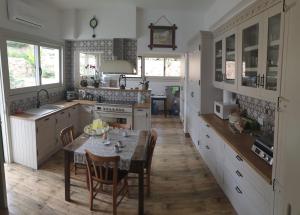 una cucina con tavolo e sedie e una cucina con armadietti bianchi di Dervise Mehmet Guest House a Lefke-Karadağ