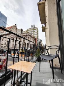 un banco y una silla en un balcón con una calle en Lead Hostel en Buenos Aires