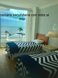 two beds in a room with a view of the ocean at Apartamento vista al mar in Boca del Río
