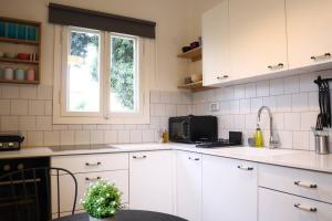 una cocina con armarios blancos y una ventana en lovely apartment in Ra'anana en Ra‘ananna