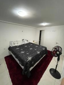 a bedroom with a bed with a black comforter and a fan at Quartos - Cíntia in Fortaleza