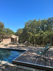 a deck with two chairs and a swimming pool at Gîte Ethic Simple & Chic in Labastide-Marnhac