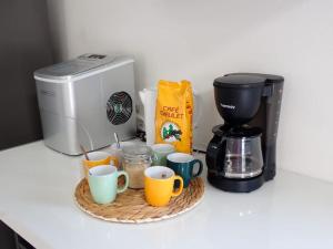 a counter top with coffee cups and a coffee maker at Villa Luciole Man'Néa in Sainte-Anne