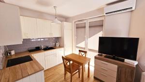 eine Küche mit einem Tisch und einem TV in der Unterkunft Apartament Młynarska in Piła