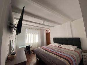 a bedroom with a bed and a desk and a television at Casa Hospedaje Cajamarca in Cajamarca