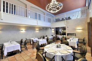 a restaurant with white tables and chairs and a chandelier at Le Domaine des Oliviers in Pierrelatte
