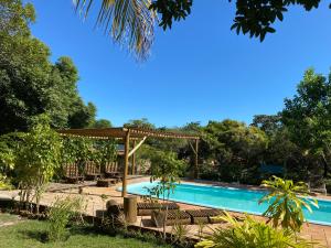 a swimming pool with a pergola next to a swimming pool at Refúgio do Corsário-Imbassai-Ba in Imbassai