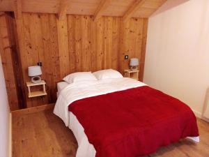 a bedroom with a bed with a red and white blanket at Chalet des Lys - tout confort - 12 personnes in Valloire