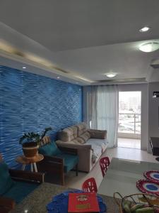 a living room with a couch and a blue wall at Quartos - Cíntia in Fortaleza