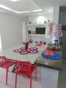 a kitchen with a table and two red chairs and a table at Quartos - Cíntia in Fortaleza