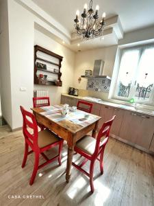 a kitchen with a wooden table and red chairs at Appartamento Grethel - Rebomaholidays in Gardone Riviera